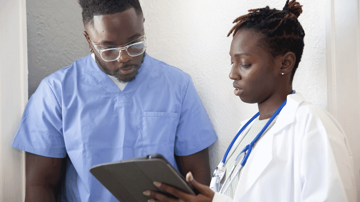 Two healthcare professionals reviewing research on a tablet